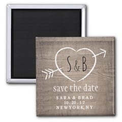 rustic save the date magnet with initials in a heart and arrow on a faux wood base