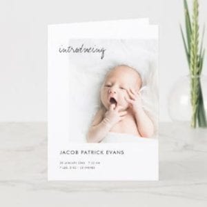 simple minimalist black and white birth announcement folded card with photo and 'introducing' in modern script
